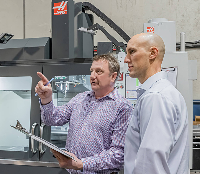 Two men directing CNC shop